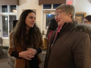 Two people talking in front of a window