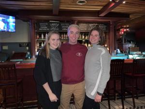 Three people standing in front of a bar