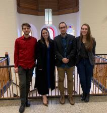 Four people smiling for a photo near a balcony