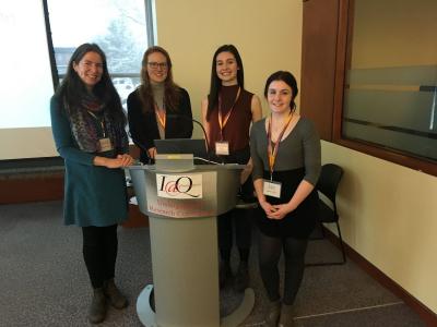 Four people sitting behind a podium with an I@Q sign