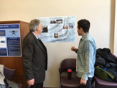 Two people talking while looking at a poster