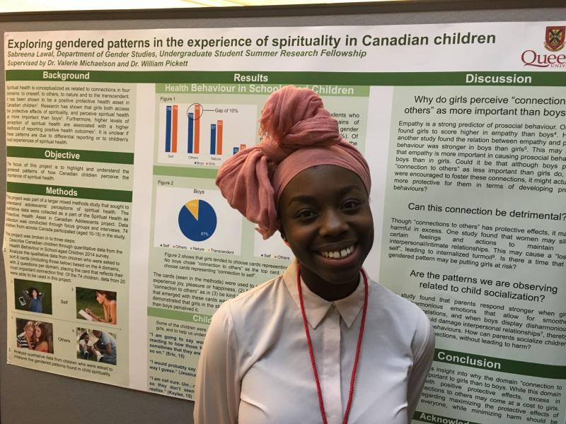 A person smiling in front of a poster