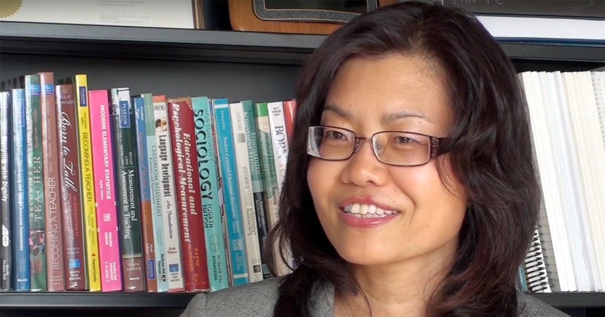 Liying Cheng in front of book shelf.