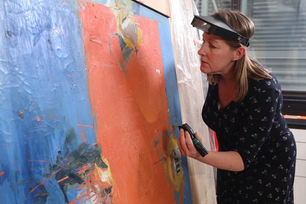 [Patricia Smithen inspecting painting]