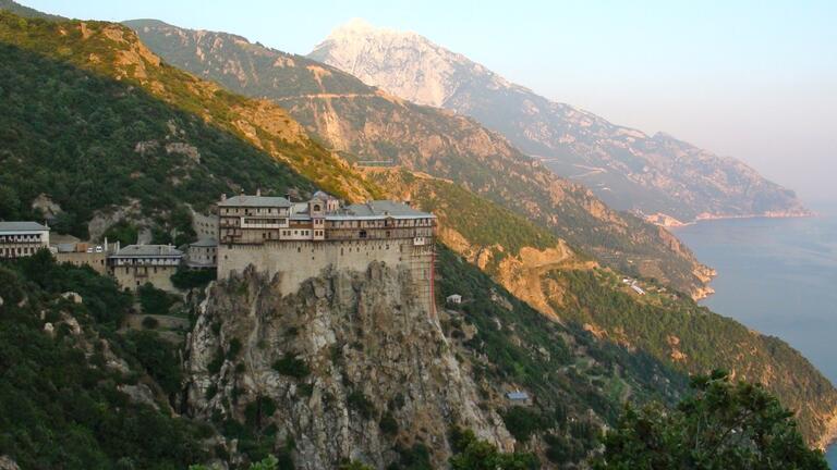 a Monastery on a cliff against a background of mountains and the ocean