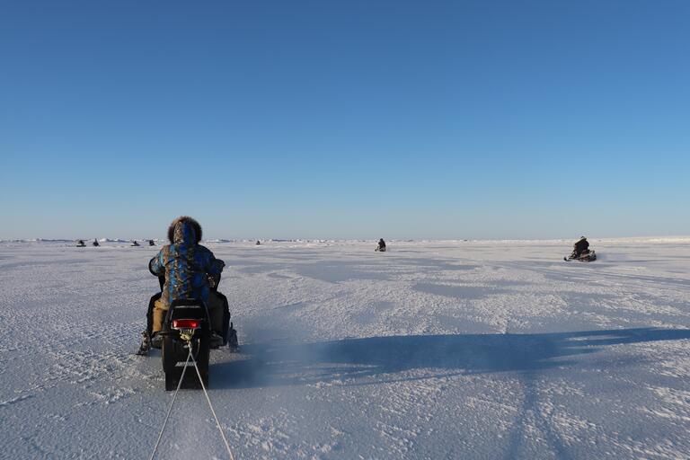 Snowmobile pulling a sled across snow