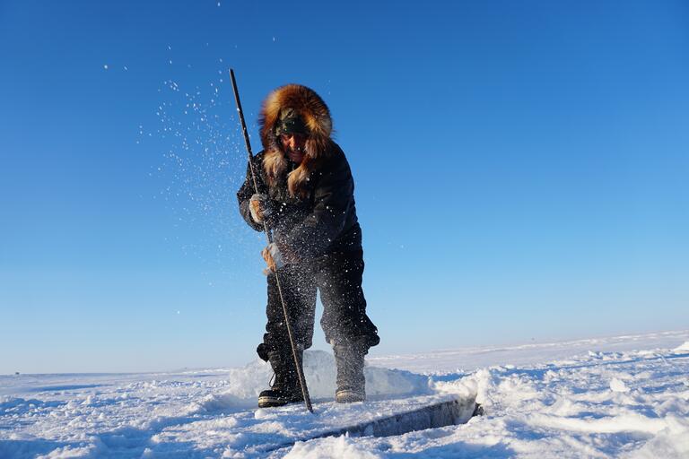 Inuit man ice fishing