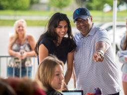 A student smiles as their parent points at the move-in welcome desk.