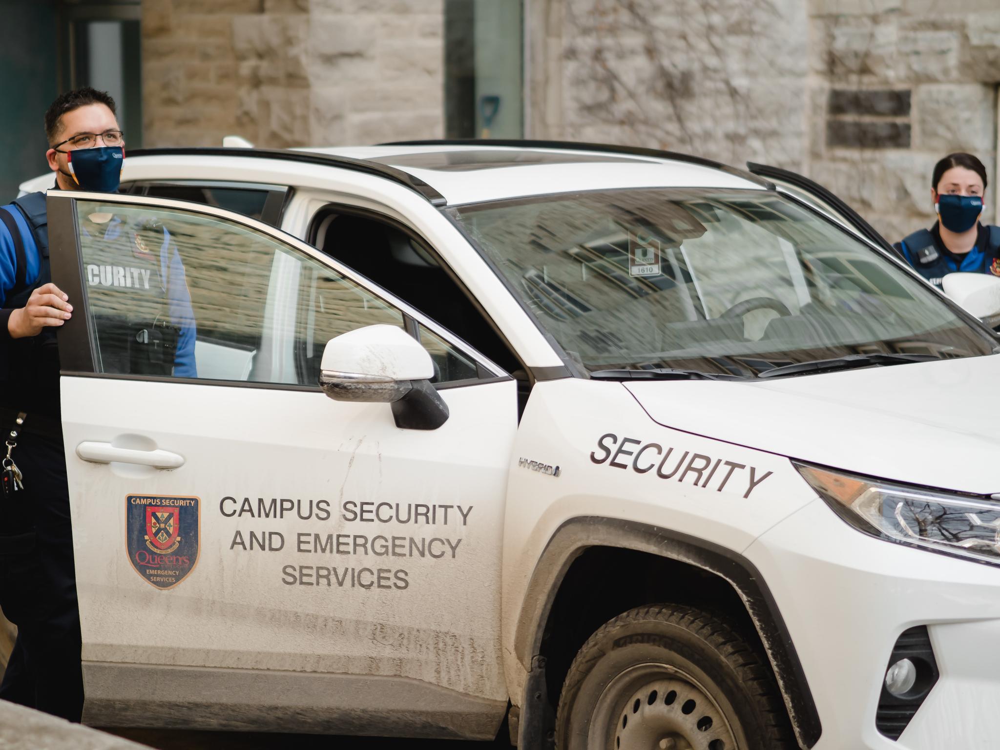Two campus security officers exiting their vehicle wearing masks