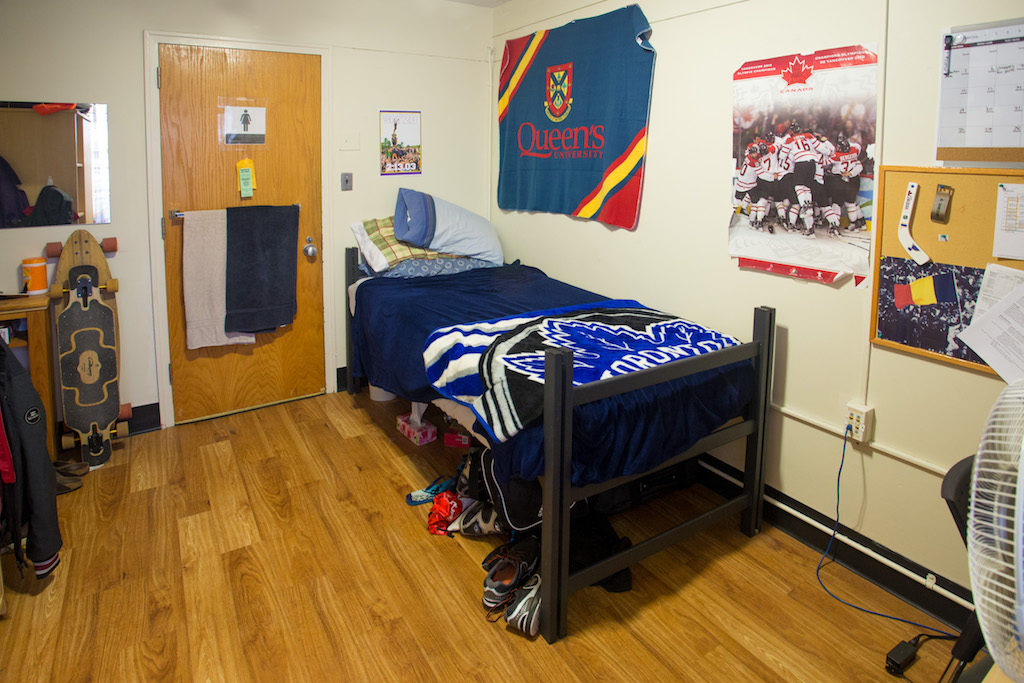Inside of Leonard Hall room. There is a bed in view, the door, and some décor on the walls. 