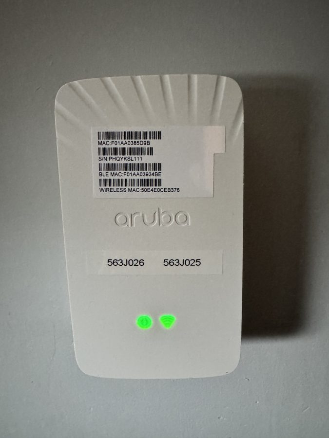 Front of a white Aruba access point mounted on the wall