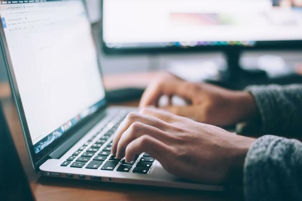 Close up of hands typing on an open laptop