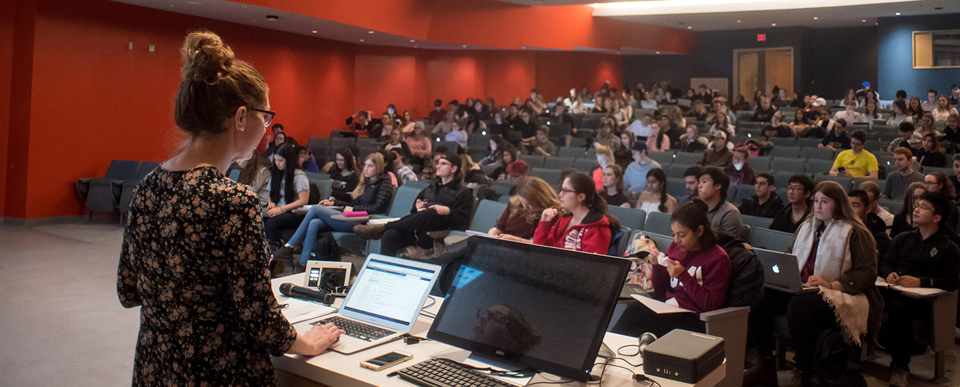 Queen's professor standing at the front of a lecture hall with students