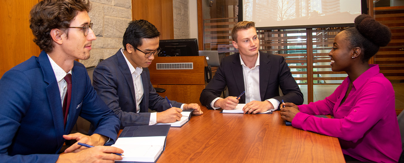 Graduate students gathered around a desk talking