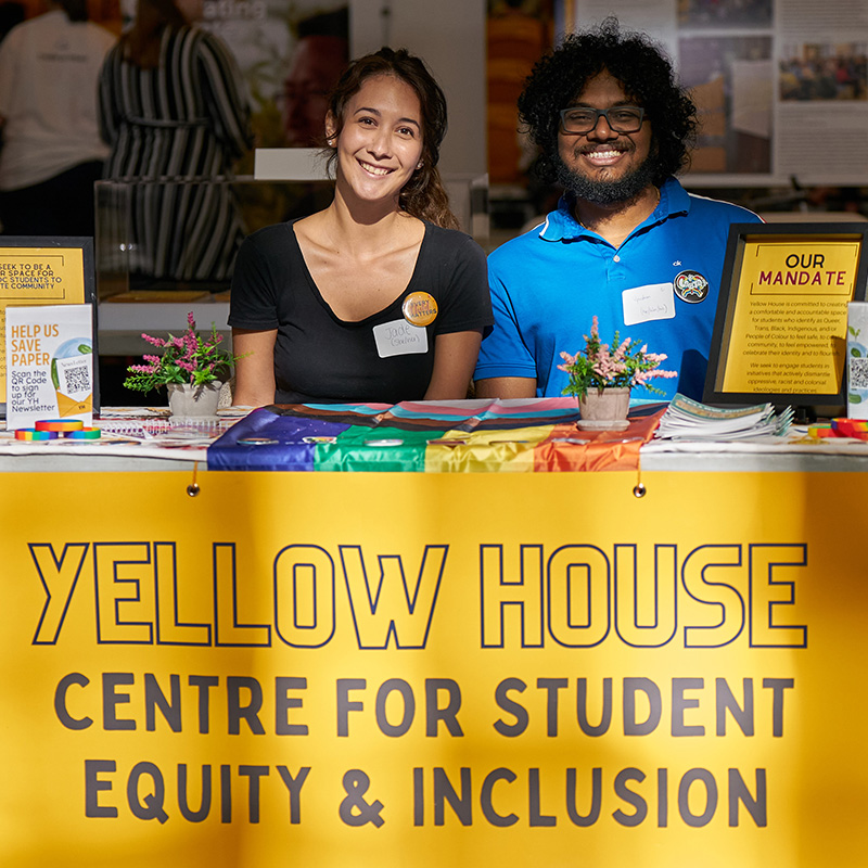 Two students sitting at yellow house booth
