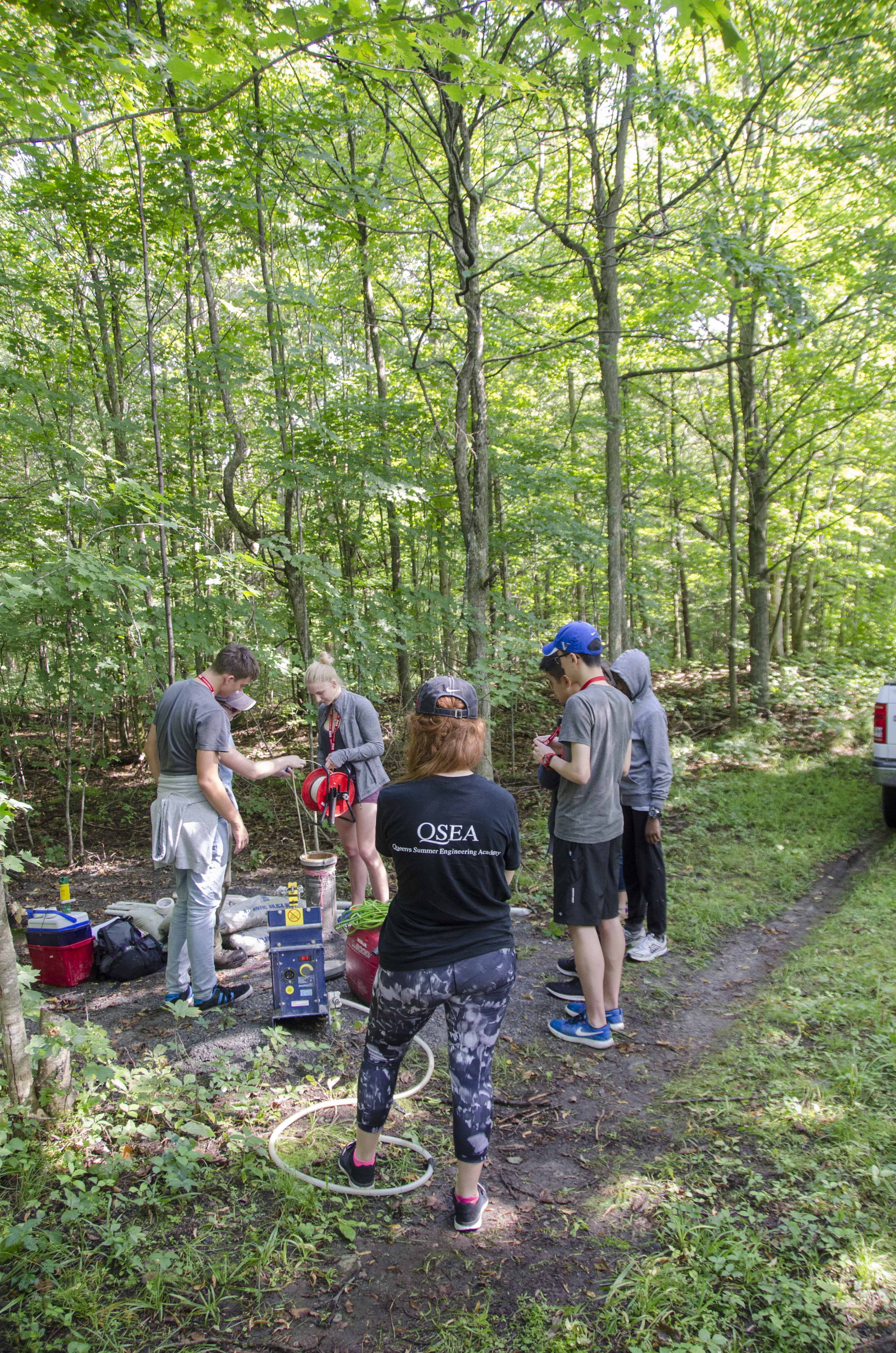 Students in forest, gathered around equipment