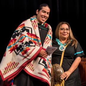 [an Indigenous graduate has just been gifted a blanket]