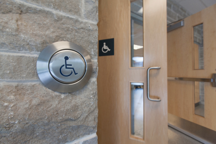 [An accessible automatic door button opens a set of two wood doors.]