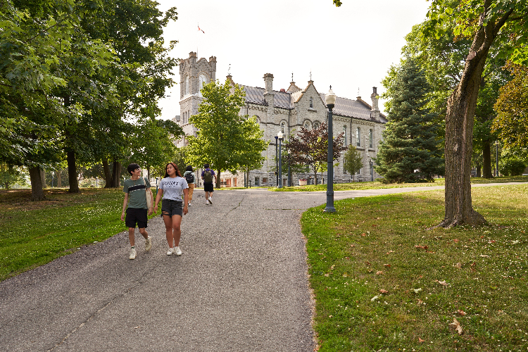 [Students walk down Founders Row on Queen’s University campus.]