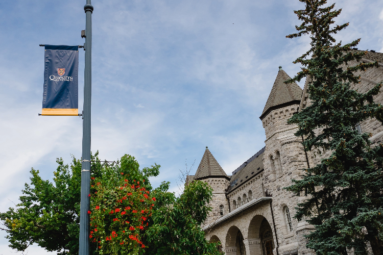 [A Queen’s University pennant attached to a light post in front of Ontario Hall. ]