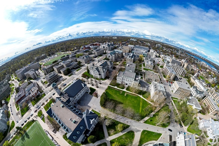 [An aerial photo of Queen’s University campus using a fisheye lens focused on Theological Hall.]
