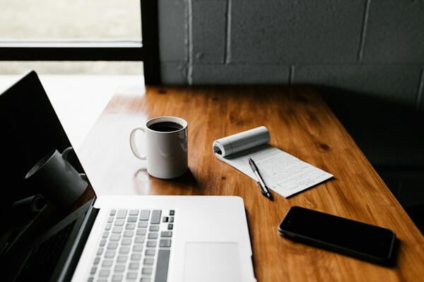 Computer, coffee cup, and notepad