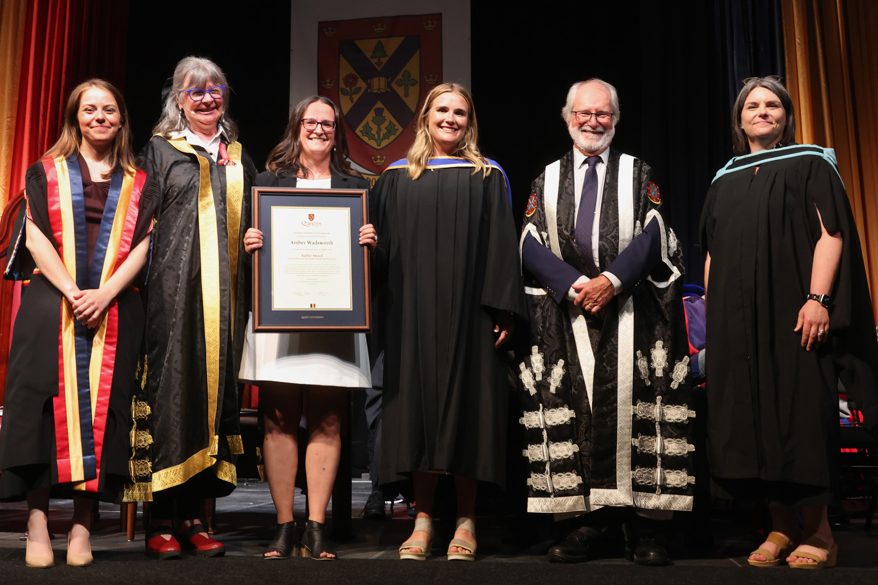 Baillie Award recipient Amber Wadsworth on stage at the Spring 2025 convocation with (from left to right) Rector Niki Boytchuk-Hale, Chancellor Shelagh Rogers, Baillie Award nominator Briar McCaw, Principal and Vice-Chancellor Patrick Deane, and Interim Vice-Provost & Dean of Student Affairs Corinna Fitzgerald.