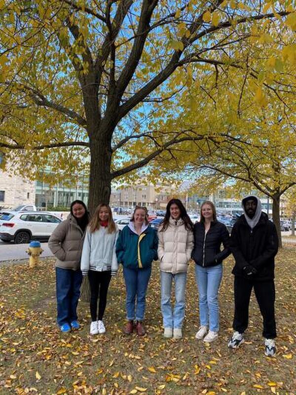 6 Student Ambassadors standing in front of tree during early November on the front lawn of Gordon Hall.
