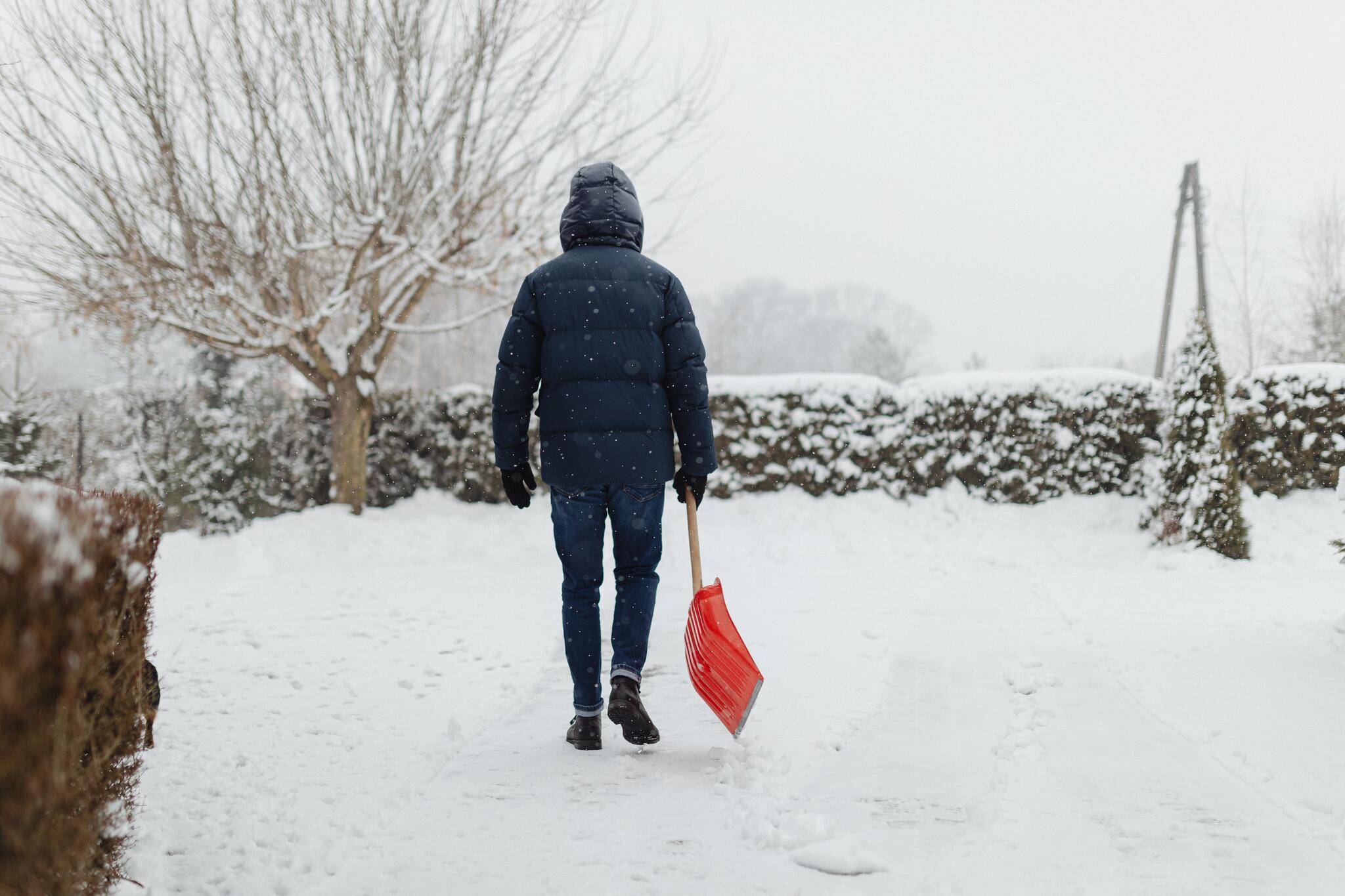 Person holding red shovel in winter
