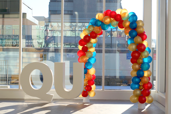 QU sign and tricolour balloon arch