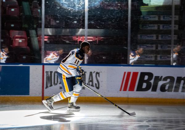 A hockey player skates under dramatic lighting