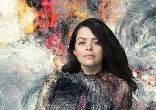 Performer poses in front of a colourful abstract background