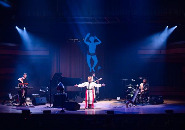 Artist NAXX BITOTA and her band on stage bathed in blue light