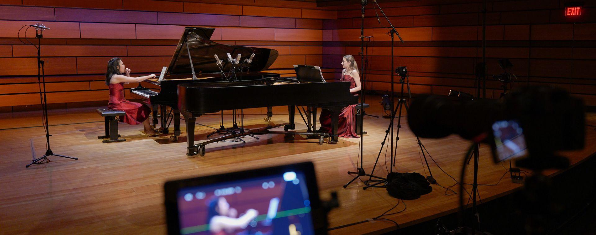 two pianists on stage with video