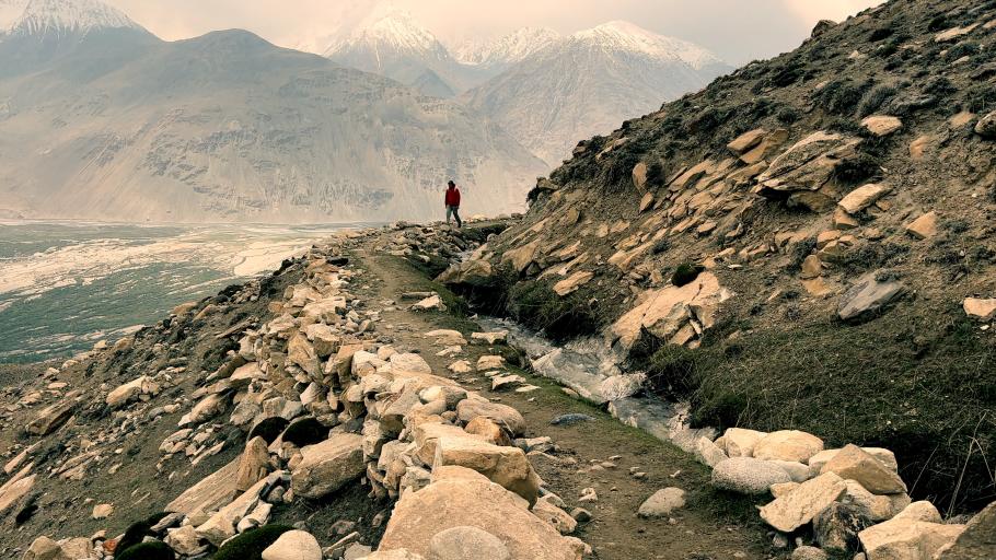 A lone figure stands on a dramatic cliffside