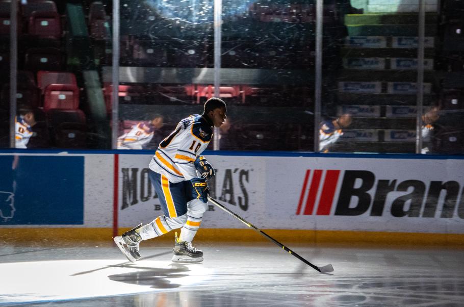 A hockey player skates under dramatic lighting