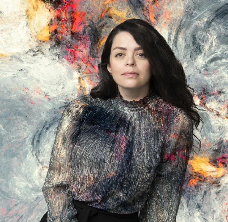 Performer poses in front of a colourful abstract background