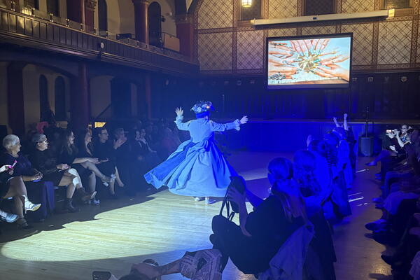 Model walking down the runway during a historical costume themed ball.