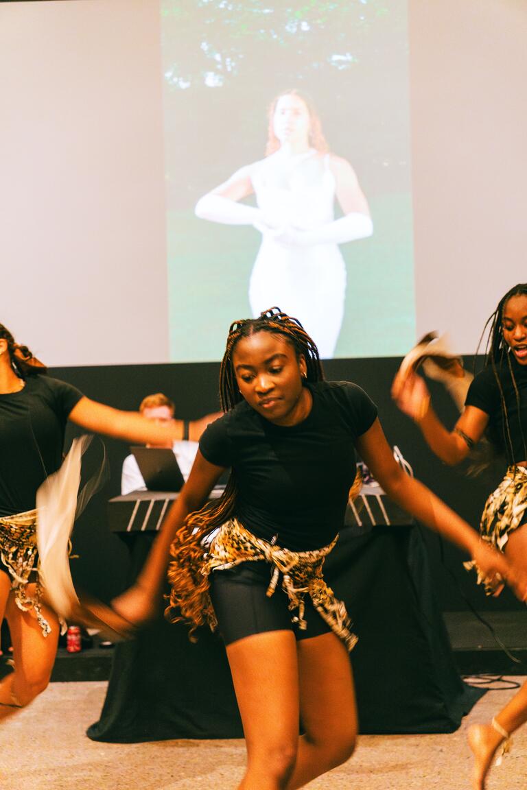 ACSA dance team mid-dance in front of a projector screen