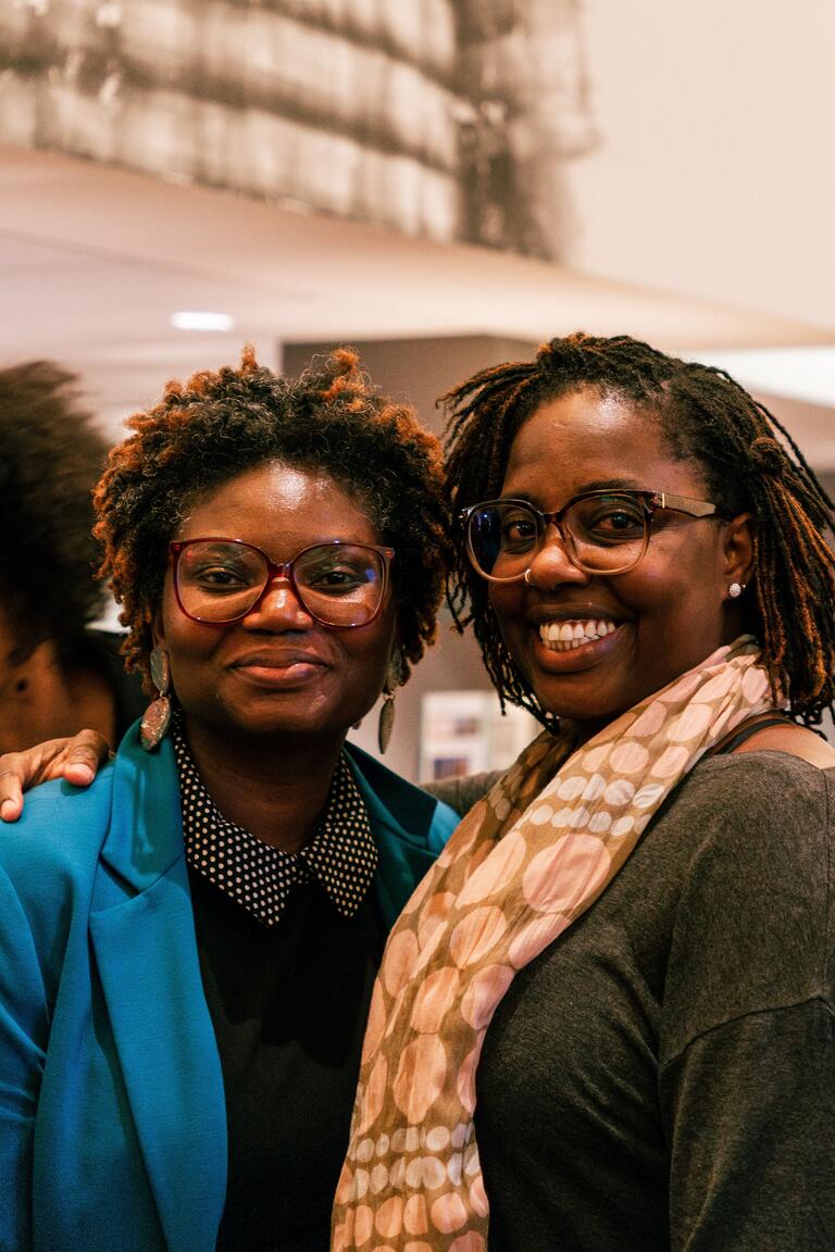 two black women posing and smiling next to eachother